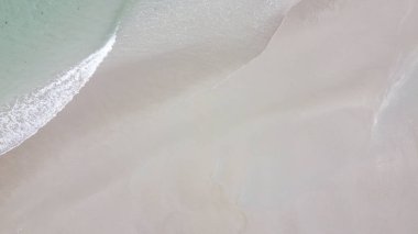 Sandy seashore, top view. Minimalistic seascape, a copy space. Wet sand. Natural background, texture. Peaceful beach background, sand and sea water. Ocean coast.