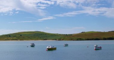County Cork, Ireland, August 21, 2022. Several small boats are anchored in Clonakilty Bay, sunny summer day. Summer seaside landscape, coastline and boats. video.