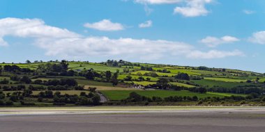White cumulus clouds in the sky over the hilly Irish countryside. Green hills on a nice summer day. Irish countryside, County Cork.