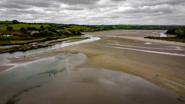 Inchydoney 'in resimli İrlanda plajı, bulutlu bir günde alçak gelgit, üst manzara. İrlanda adasının kıyı şeridi. Atlantik Okyanusu 'ndaki güzel yeşil tepeler. Gökyüzündeki gri bulutlar.