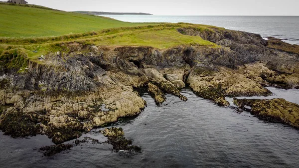 爱尔兰大西洋海岸上一个风景如画的岩石斗篷 海滨风景 在水体旁边的绿草场 — 图库照片