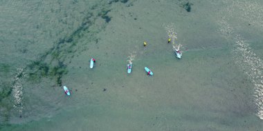 Denizin yüzeyinde sörf tahtaları olan sörfçüler büyük dalgaları ve manzarayı bekliyorlar. İnsanlar su sporları yapıyor. Sörfçüler. Deniz Burnu. Yeşil yosun kümesi, İHA 'dan bir fotoğraf..