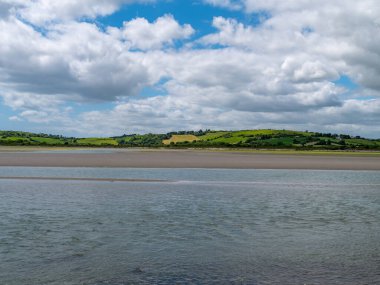 İrlanda kırsalının tepesinde gökyüzünde beyaz kümülüs bulutları. Yeşil tepeler güzel bir yaz gününde. İrlanda kırsal bölgesi, County Cork.