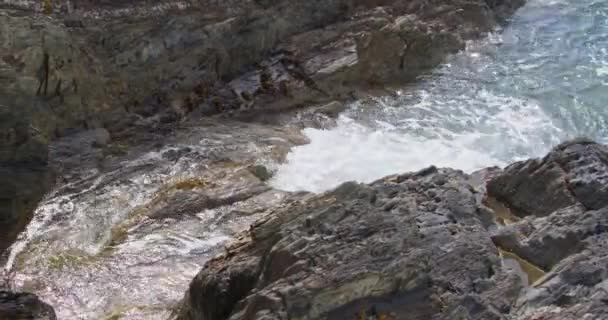 Woda Rozpyla Się Poszarpane Skały Tworząc Pianę Wzdłuż Wybrzeża — Wideo stockowe