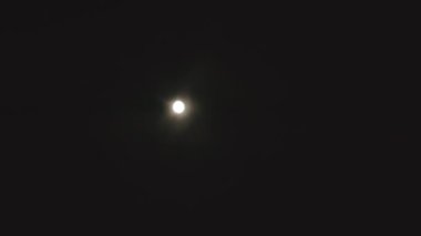 Bulutlu bir gece gökyüzünün videosu. Ortasında parlak bir dolunay var..
