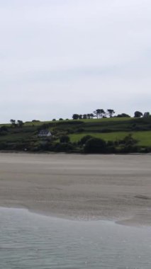 Alçalma dalgası İrlanda 'nın okyanus kıyısındaki kumlu ovaları ortaya çıkarıyor. Dikey video.