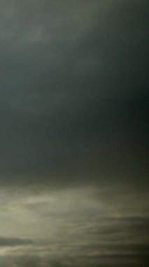 Doğanın dramı: hızlı hareket eden, uğursuz bulutlar zaman atlaması içinde gökyüzünde yarışıyorlar. Dikey video.
