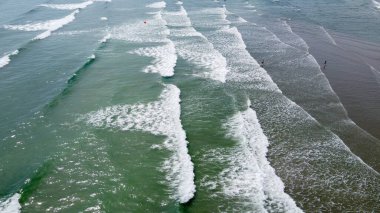 Deniz dalgaları, en üst manzara. Suyun yüzeyinde beyaz deniz köpüğü. Plajın havadan görünüşü