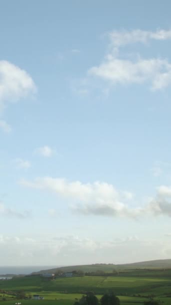 緑のアイルランドの丘の上の青い空に対して速く動く白い積雲のイメージは タイムラプスのビデオで捉えられました 垂直ビデオ — ストック動画