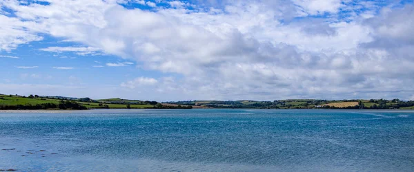 夏の日には 海岸の上空に白い積雲がたくさんあります アイルランドの海辺の風景 青い空と白い雲の下の青い海 — ストック写真