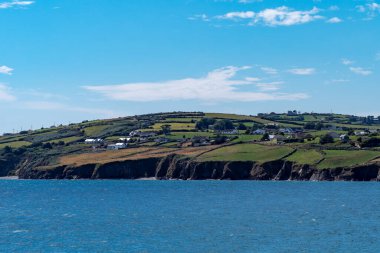 Güneşli bir yaz gününde Atlantik Okyanusu 'nun kayalık kıyısında bir İrlanda yerleşimi. Deniz manzarası, mavi gökyüzünün altındaki mavi deniz..