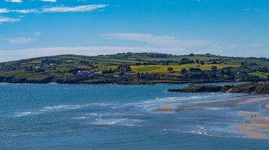 Güneşli bir yaz gününde ünlü İrlandalı Inchydoney plajı manzarası. İrlanda 'nın güzel Atlantik kıyıları. Yazlık tatil köyü, manzara, deniz manzarası. Deniz kıyısında açık mavi gökyüzü