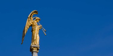 Gökyüzüne karşı boru çalan bir meleğin yaldızlı heykeli. Uzayı kopyala Kilise sütununun tepesindeki bir melek heykeli.