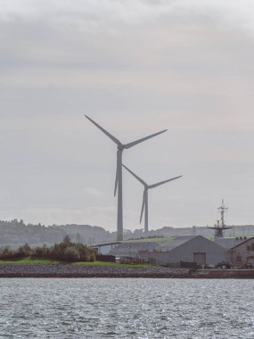 İrlanda 'da rüzgar jeneratörleri, manzara. Ringaskiddy, County Cork 'ta iki rüzgar türbini bulundu. Bulutlu bulutlu gökyüzü. Bulutlu gökyüzünün altında rüzgar türbini