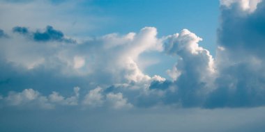 Mavi gökyüzünde tüylü kümülüs bulutları.