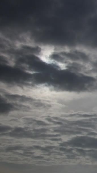 太陽は厚い灰色の雨の雲を通して輝いて 空の背景のようなものです 層状の雲は しばしば暗いハニカム状の外観を持つ灰色または白色のパッチ状の雲である 垂直ビデオ — ストック動画