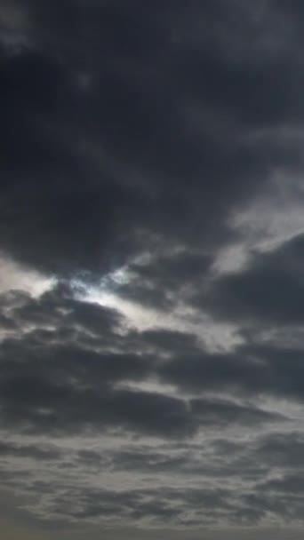 太陽は厚い灰色の雨の雲 空の背景を通して輝いている 層状の雲は しばしば暗いハニカム状の外観を持つ灰色または白色のパッチ状の雲である 垂直ビデオ — ストック動画