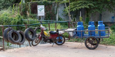 Siem Reap, Kamboçya, Aralık 2018. Bir römorkla donatılmış, gaz silindirleriyle dolu, verimli ve alışılmadık bir ulaşım aracını gösteren klasik bir motosiklet..
