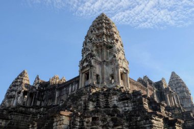 Kamboçya 'daki Angkor Wat Khmer Tapınağı' nın yüksek madalyalı taş kulesi açık mavi bir gökyüzünün altında..