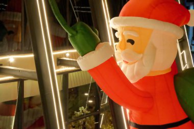 Bir binanın duvarına tırmanan kocaman şişme bir Noel Baba figürü..