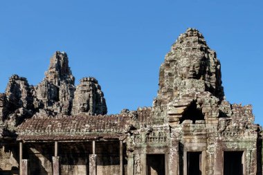 Kamboçya 'da güneşli bir gökyüzünün altında antik Bayon Tapınağı' nın insan yüzlü taş kuleleri..