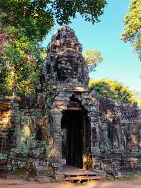 Banteay Kdei 'nin eski Khmer tapınağına giden insan yüzleri ile süslenmiş yüksek bir taş kemer..