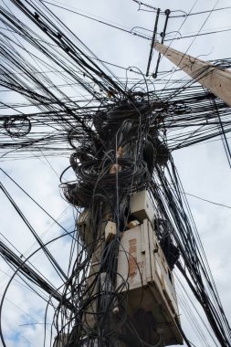 Image showcasing a considerable multitude of intertwined electric cables, representing the disorderly urban electrical networks prevalent in Asia.