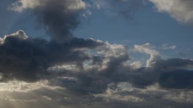 Mavi sabah gökyüzü hızla hareket eden kümülüs bulutlarıyla doludur. Bulutlar bu zaman dilimi videosunda arkaplan görevi görüyor.