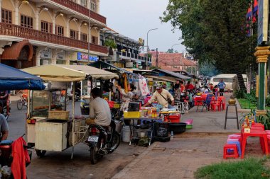 Siem Reap, Kamboçya, 22 Aralık 2022. Canlı Kamboçya Pazarı: Kamboçya 'da renkli bir sokak pazarı, satıcılar alışveriş arabalarının yanında koşturuyor.
