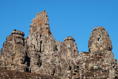 Kamboçya 'daki Ortaçağ Khmer Bayon Tapınağı' nın taş kuleleri açık mavi gökyüzüne karşı.
