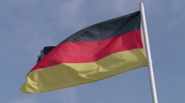 Almanya bayrağı rüzgarda sallanıyor açık bir gökyüzüne, bayrak direğinde Alman bayrağı.