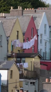 İrlanda 'nın Cobh kasabasındaki şirin renkli evlerin arka planında çamaşırları kurutmak. Dikey video.