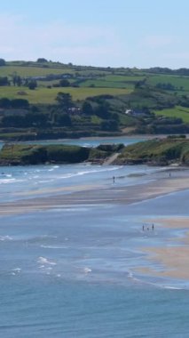 Sıcak bir yaz gününde, County Cork 'taki enfes kumlu Inchydoney plajında nefes kesici İrlanda kıyı şeridi sergilenir. Dikey video.