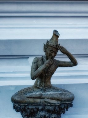 Bangkok 'taki huzurlu tapınak bahçesinin ortasında, küçük bronz bir heykel, Tayland' ın geleneksel kendi kendine masajı yapan bir adamı tasvir ediyor..