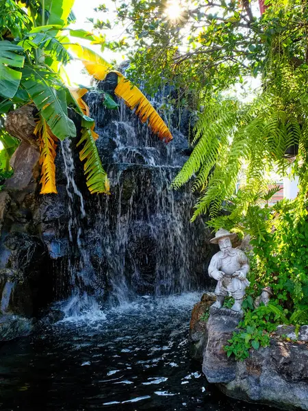 在泰国一座古寺的宁静的圣地内 一个亚洲花园展现了一个风景如画的角落 上面点缀着瀑布般的瀑布和精美的公园雕塑 营造出一副美丽的景象 — 图库照片