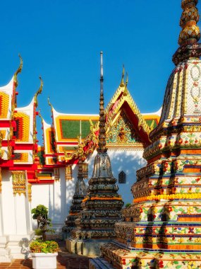 Tayland 'daki tapınak kompleksi. Tapınak kompleksi birden fazla süslü çitten oluşur. Çediler altın ve renkli fayanslarla süslenmiş. Gökyüzü mavi ve hava açık..