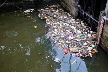 Bangkok, Tayland, 28 Aralık 2018. Kirlenmiş bir su kütlesi, plastik şişeler ve teneke kutularla dolu, beton bir duvara karşı..