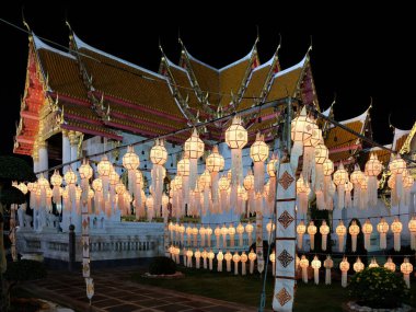 Gece bir Tayland tapınağı, beyaz fenerlerle süslenmiş, sıcak ve huzurlu bir parıltı yayıyor..
