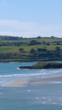 İrlanda 'nın County Cork kentindeki Inchydoney plajının manzaralı güzelliği, altın kumları ve berrak sularıyla ziyaretçiler için bir ziyafettir. Dikey video.