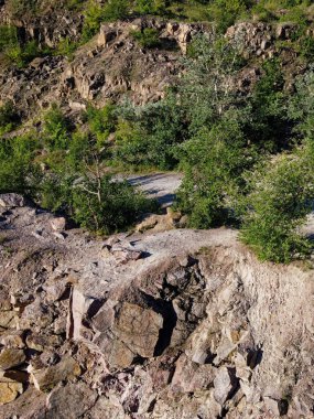 Tepenin kayalık yamaçları çalılar ve küçük ağaçlarla kaplıdır. Kayalık arazi, hava manzarası.