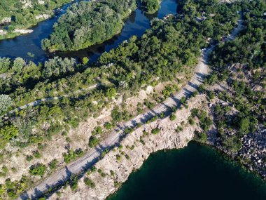 Güneşli bir yaz sabahında Radon Gölü 'nün Rocky kıyısında. Sel basmış eski bir granit ocağının hava manzarası. Resimli bir gölet..
