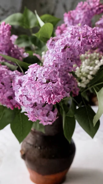 A vase of lilac flowers on a table. Lilac bouquet in a ceramic vase on the table.