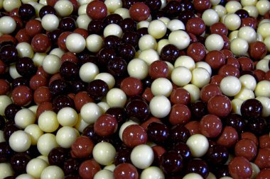 Kırmızı ve beyaz yuvarlak şeker yığınının yakın çekimi. Parlaklar ve sert bir kabukla kaplanmış gibi görünüyorlar..