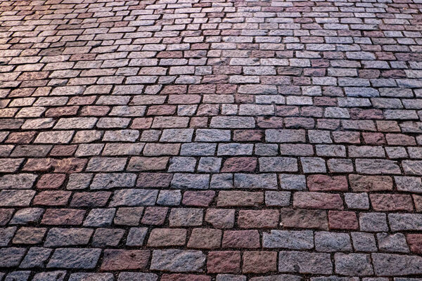 A high-angle view of a herringbone patterned brick pavement.