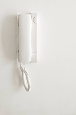 Beyaz bir telefon beyaz bir duvara monte edilmiştir..