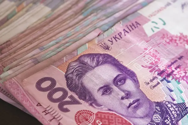 Bu resimde Ukrayna Hryvnia banknotlarının çeşitli mezhepleri ve renkleri, özellikle 200 hryvnias mezhebine odaklanarak, bir yığın notla sergilenmektedir..
