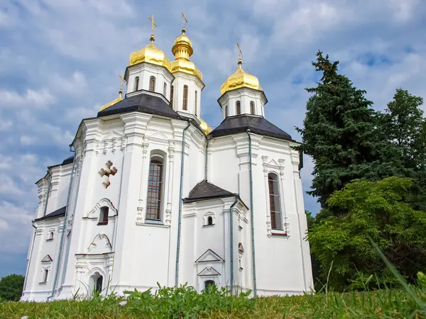 セントキャサリン正教会は 周囲の緑豊かな緑と静かな青空との完璧な調和に立っているので 金色のドームと十字架を持つ絶妙な白い教会です — ストック写真