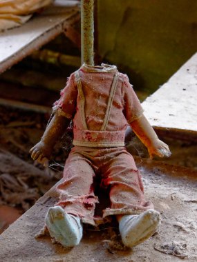 Terk edilmiş bir binada esnek kolları ve yırtık elbiseleri olan bir bebek. Kafası olmayan çocuklar için. Çernobil 'deki radyasyonla kirlenmiş bir anaokulundan kirli, kırık bir çocuk oyuncağı..