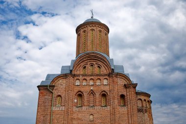 Chernihiv 'deki Cuma Kilisesi, tarihi bir tuğla kule, kayan bulutlarla dolu dingin mavi bir gökyüzünün zeminine karşı katıksız bir tezat içinde duruyor..