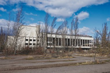 Grafiti ile terk edilmiş bir yapı, dağınık bulutlu mavi bir gökyüzünün altında. Energetik Kültür Sarayı, Pripyat 'ta terk edilmiş, çok işlevli bir kültür sarayı..